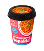 Cup of creamy & spicy topokki with visible branding on a white background