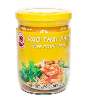 A jar of Cock Brand Pad Thai Sauce with a yellow lid and label featuring an image of Pad Thai noodles with shrimp, vegetables, and a description in English and French.