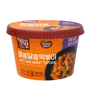 A cup of Dongwon Spicy and Sweet Topokki, showing the product packaging which is predominantly orange and black with an image of the noodles and sauce.