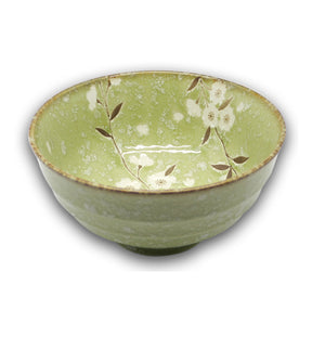 A green porcelain Japanese bowl with cherry blossom floral patterns inside.