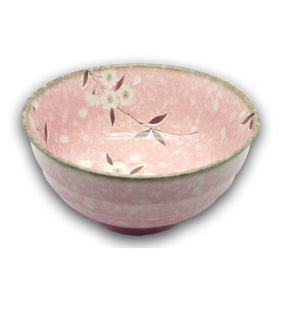 A pink Japanese porcelain bowl with cherry blossom patterns and a green rim.
