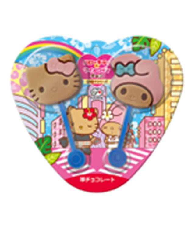 A heart-shaped Sanrio Hello Kitty product package containing two small Hello Kitty-themed items, likely hair clips or accessories, with colorful cartoon artwork on a plain white background.