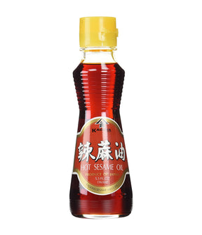 A bottle of Kadoya Hot Sesame Oil with a yellow cap, predominantly red label, and a clear display of the oil inside.