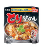 Front-facing package of Japanese instant rice with vegetables and meat, showing a bowl of prepared rice on the front with large red and white Japanese text and a dark background.