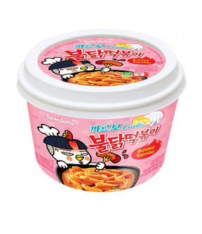 A packaged product of Samyang Buldak Topokki (Carbo) showing the product name and an image of the spicy noodles on a pink background.