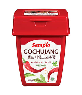 A container of Sempio Gochujang Korean Chili Paste, 500g size, with red and green colors on the label and a vegan icon.