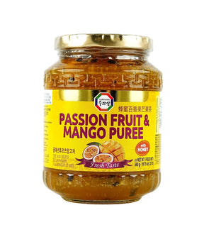 Jar of passion fruit and mango puree with a gold lid on a white background