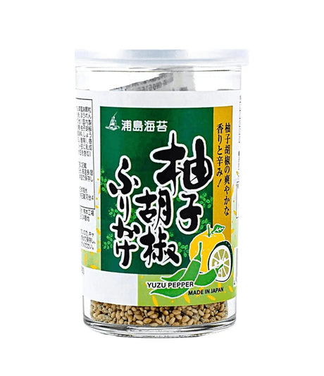 A clear plastic jar of Yuzu Pepper seasoning with a green and white label featuring Japanese text and a yellow lemon illustration, containing brownish seasoning flakes visible at the bottom.
